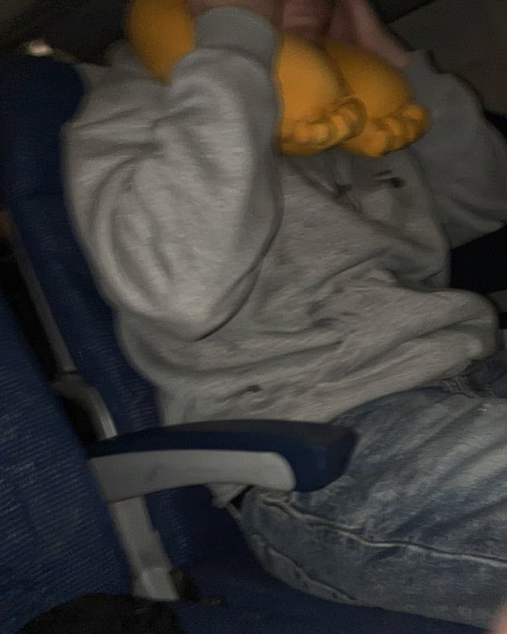 Passenger sleeping in a plane seat with the GyatFoot pillow
