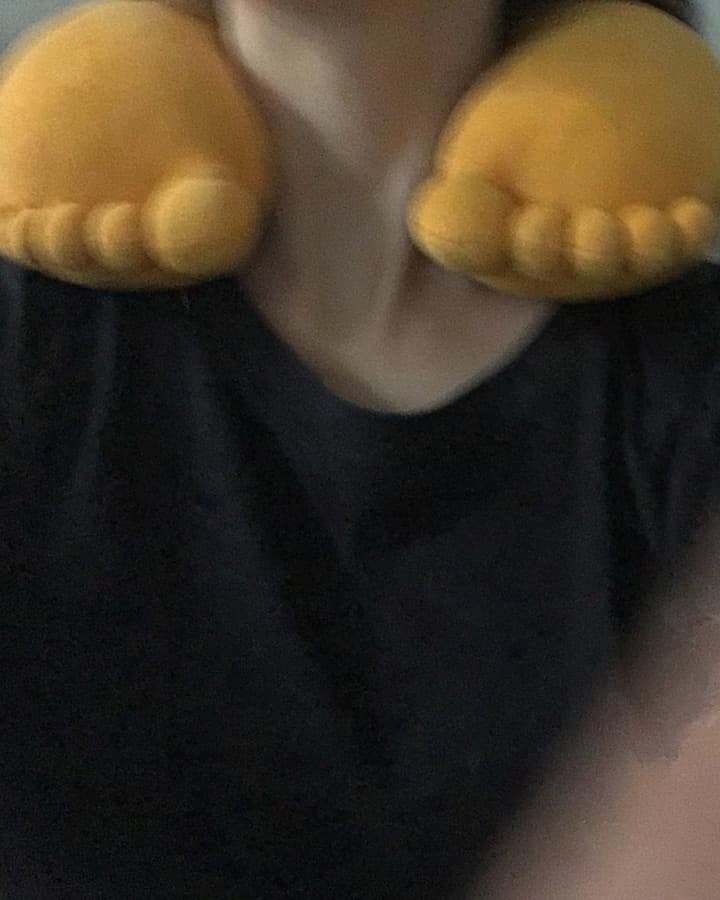 Close-up of a GyatFoot pillow worn around the neck over a dark T-shirt